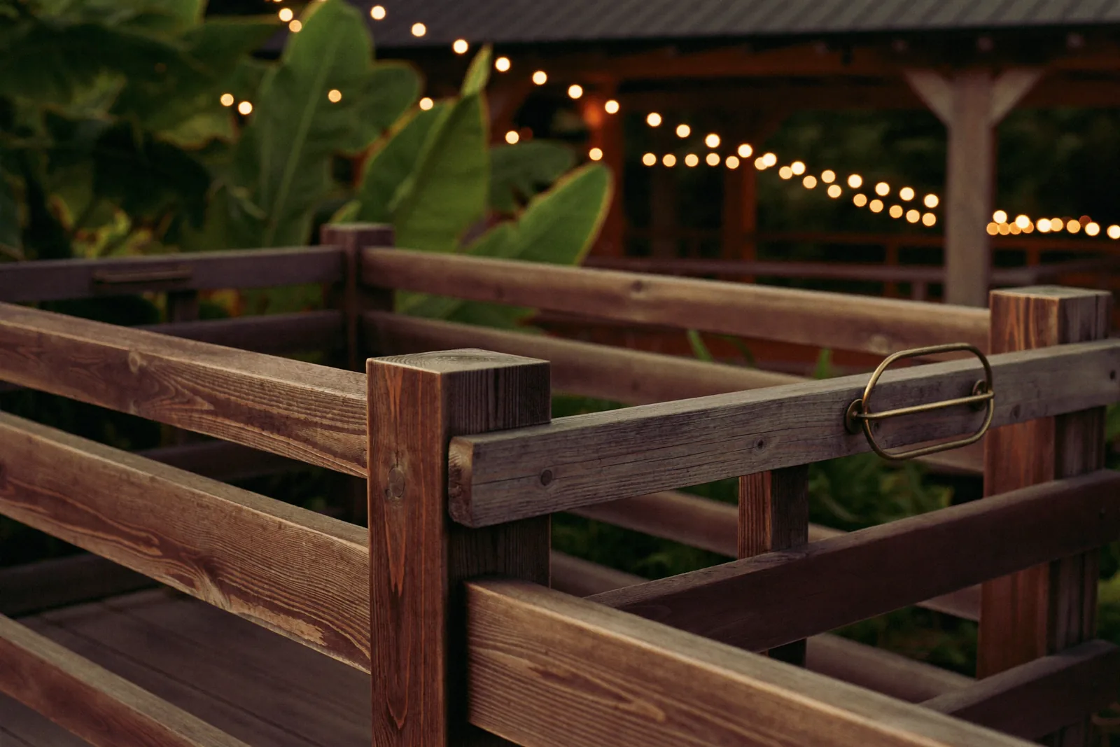 Weathered timber railing and vintage ticket booth at a family attraction at dusk, softly lit by string lights.