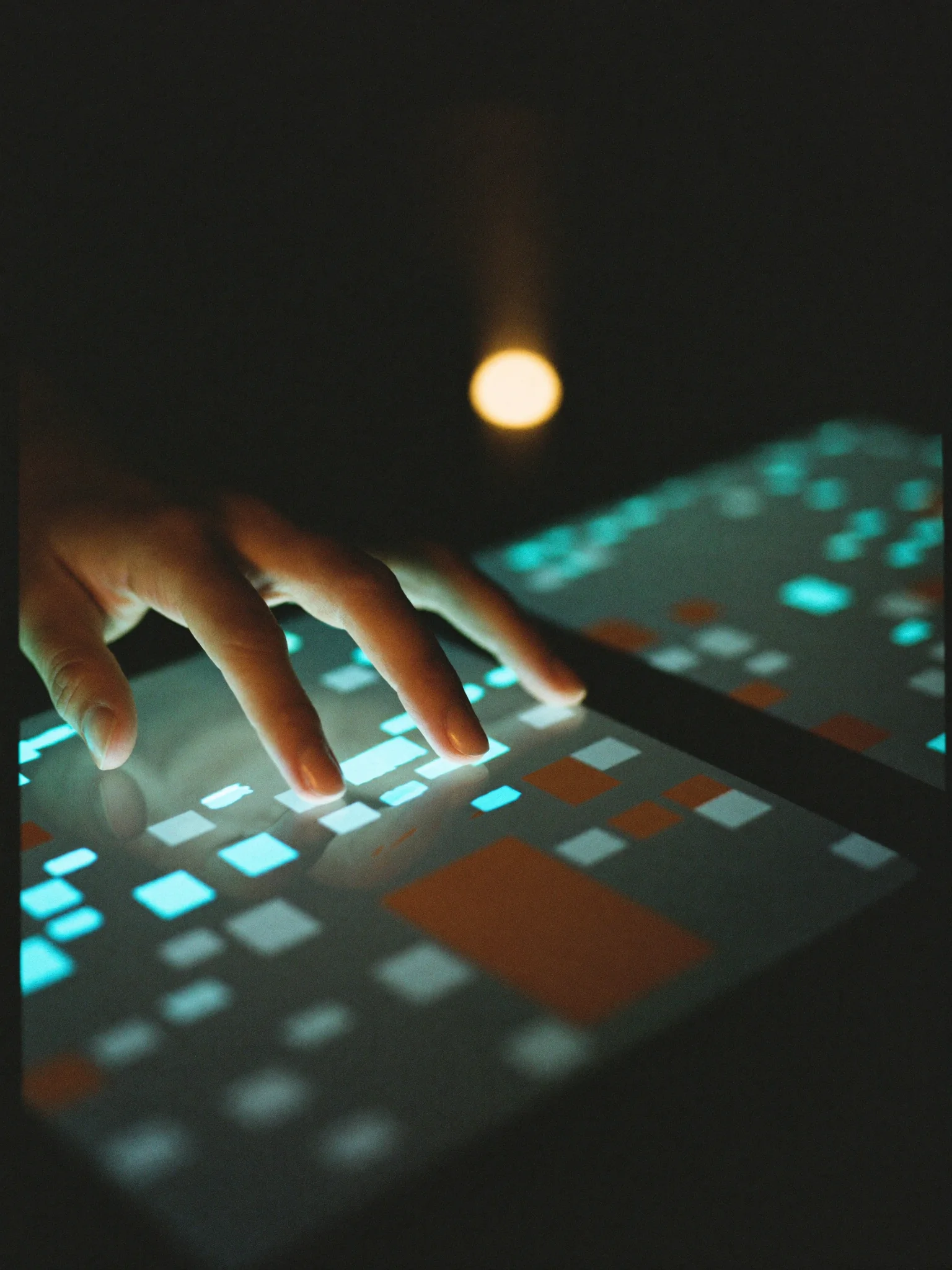 A hand resting on a tablet showing a live operations dashboard of data blocks.
