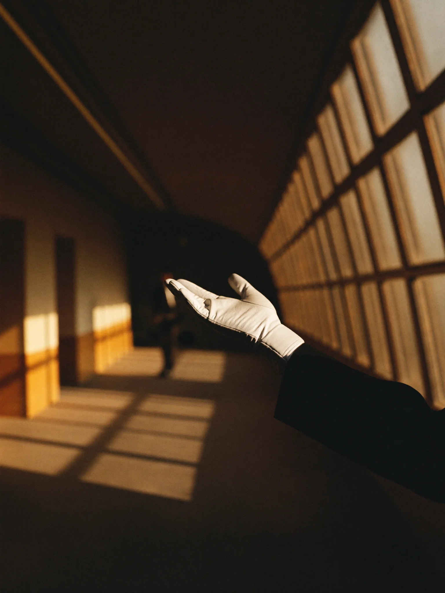 A white-gloved hand extended in a sunlit corridor, the posture of white-glove hospitality.